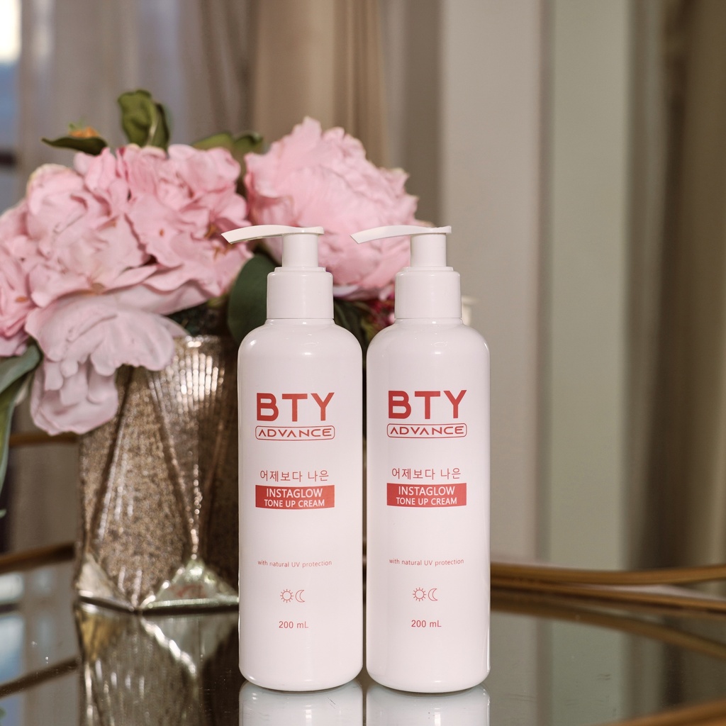 Two BTY Advance Instaglow Tone Up Cream bottles on a table with pink flowers
